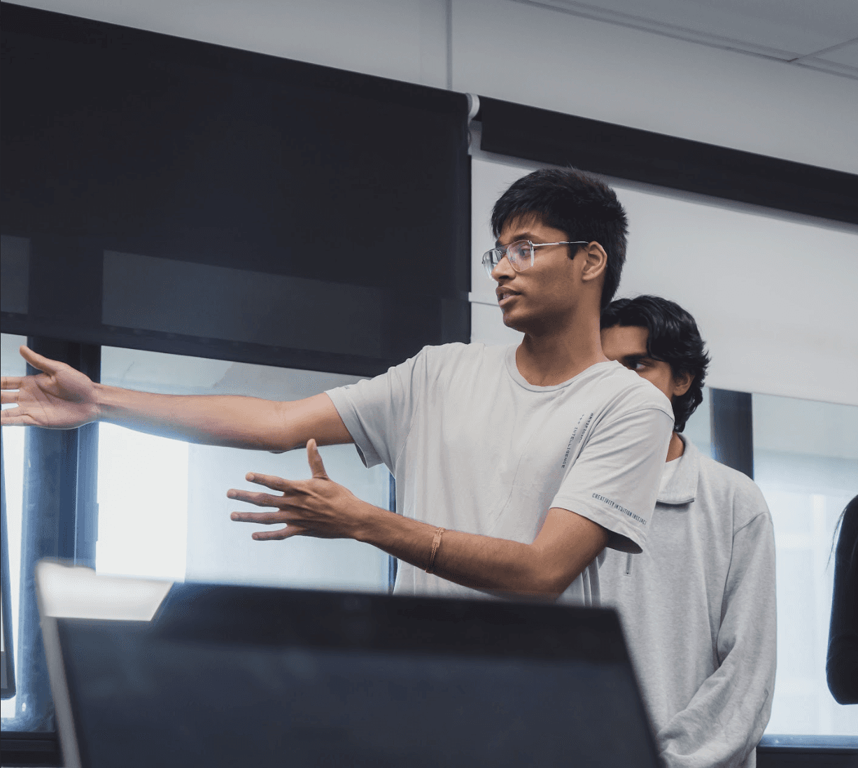 Gautham talking through the flow at a screen during a critique session, a teammate beside him.