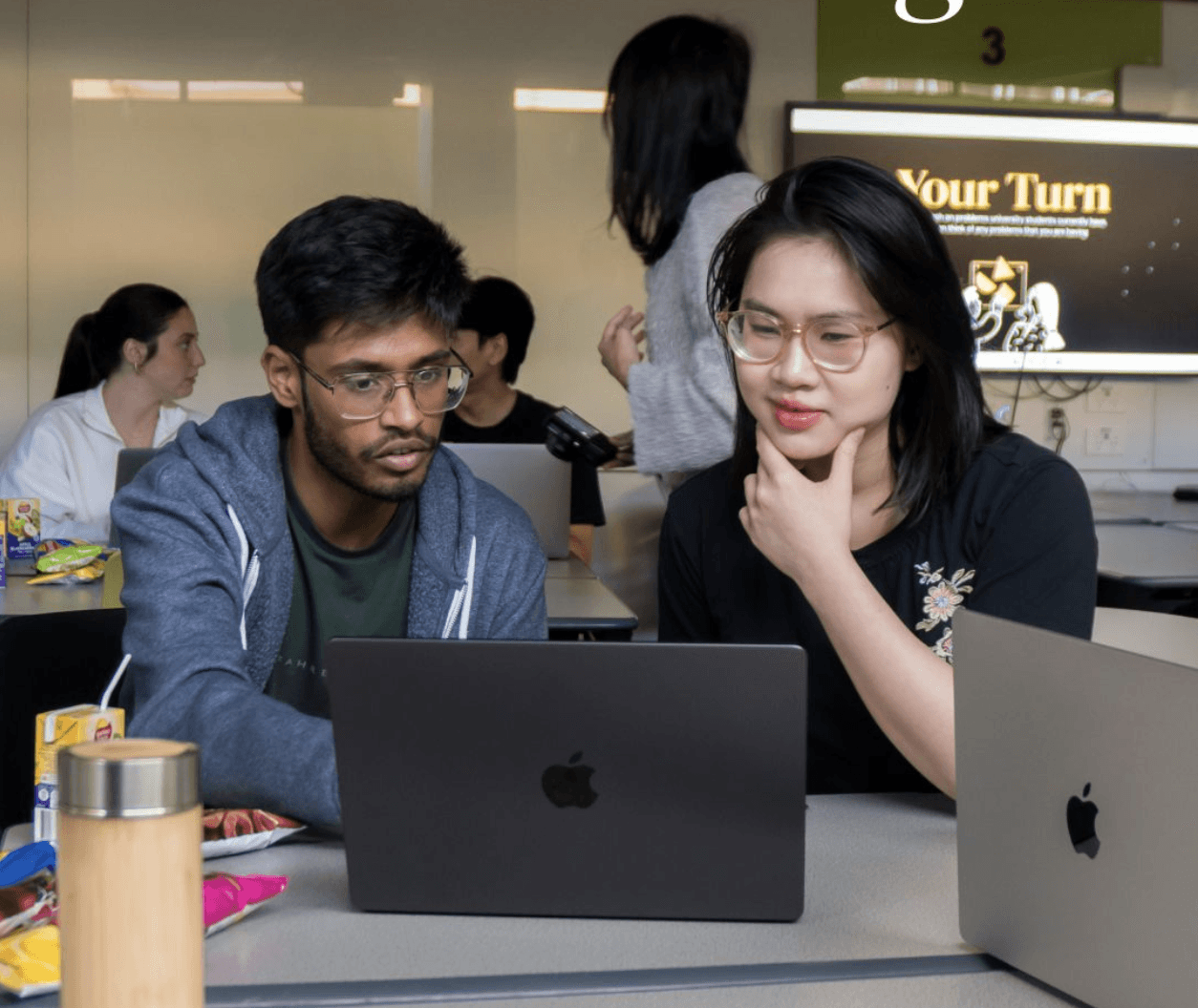 Two teammates reviewing research together at a laptop during a workshop session.