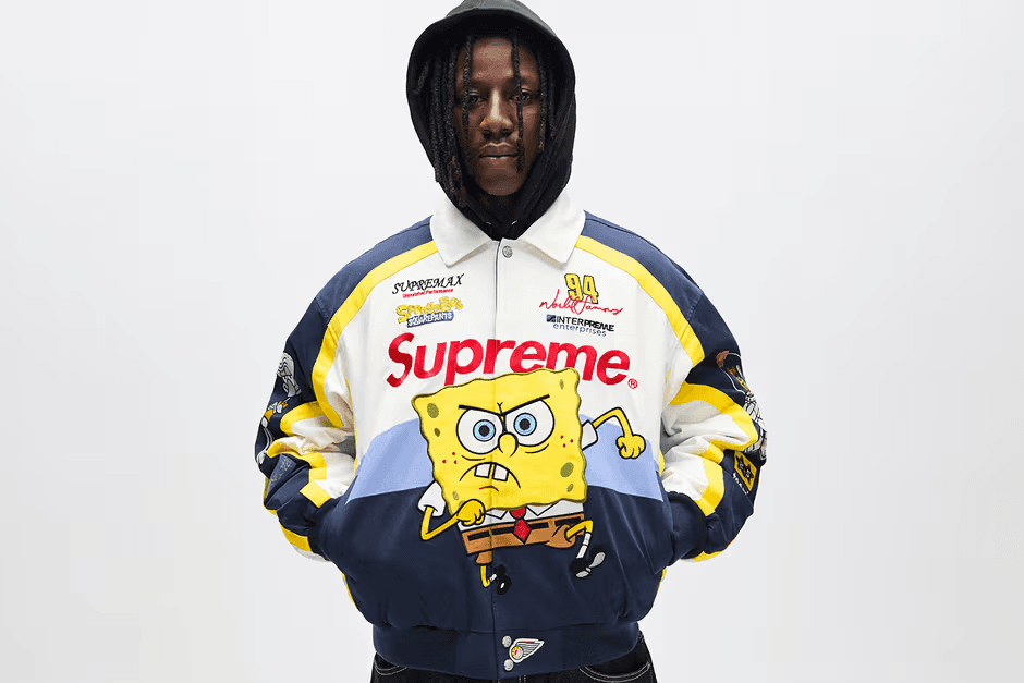 A collector wearing a rare hyped streetwear jacket, standing against a plain studio backdrop.
