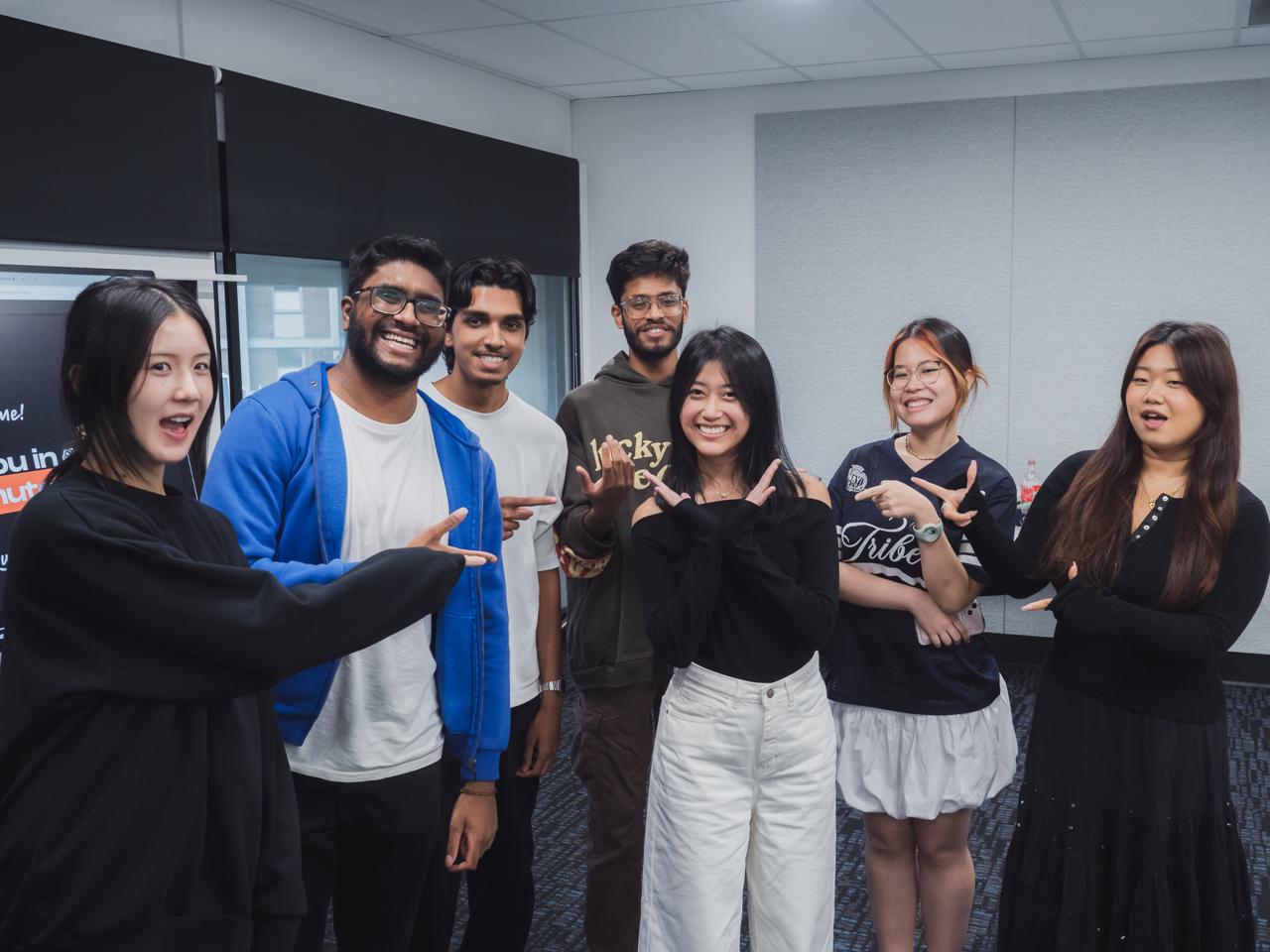 The six-person AUTHNTCT team standing together, making the brand's hand gesture.