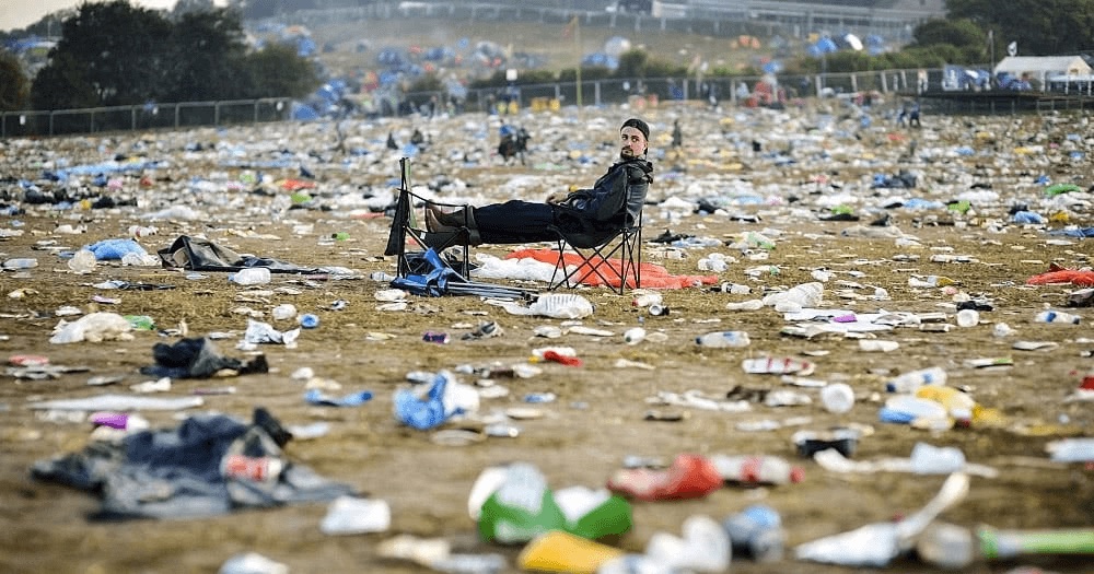 A festival field the morning after, carpeted in discarded cups and litter.