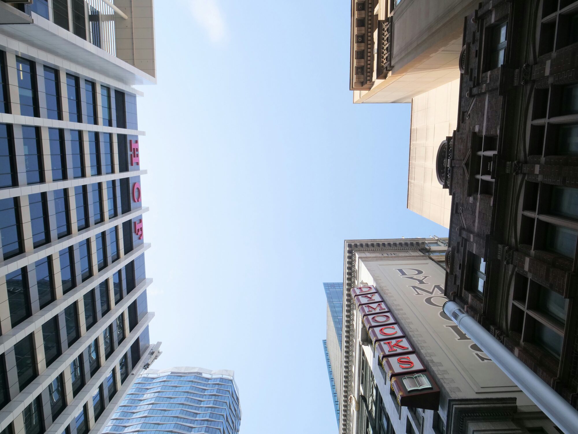 Looking up at Sydney CBD towers against a clear sky, where dense construction concentrates the urban heat island effect.