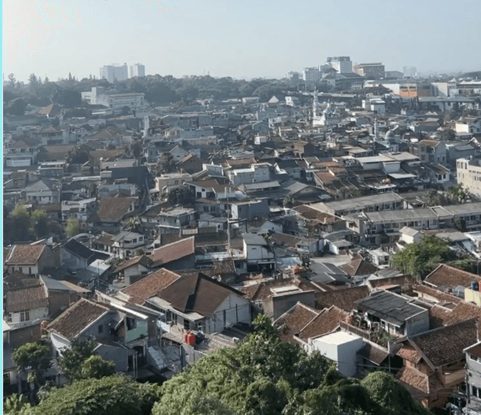 Aerial view of the dense rooftops of Lebak Siliwangi against the Bandung skyline.