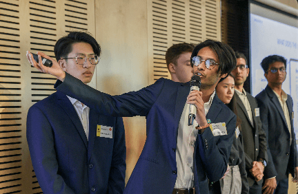 The Sherlocked.ai team presenting to the judging panel, one member holding a microphone mid-pitch.