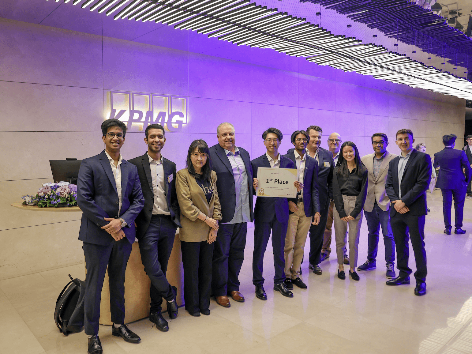 The team with judges and mentors at the KPMG office in Sydney, holding the first-place certificate.