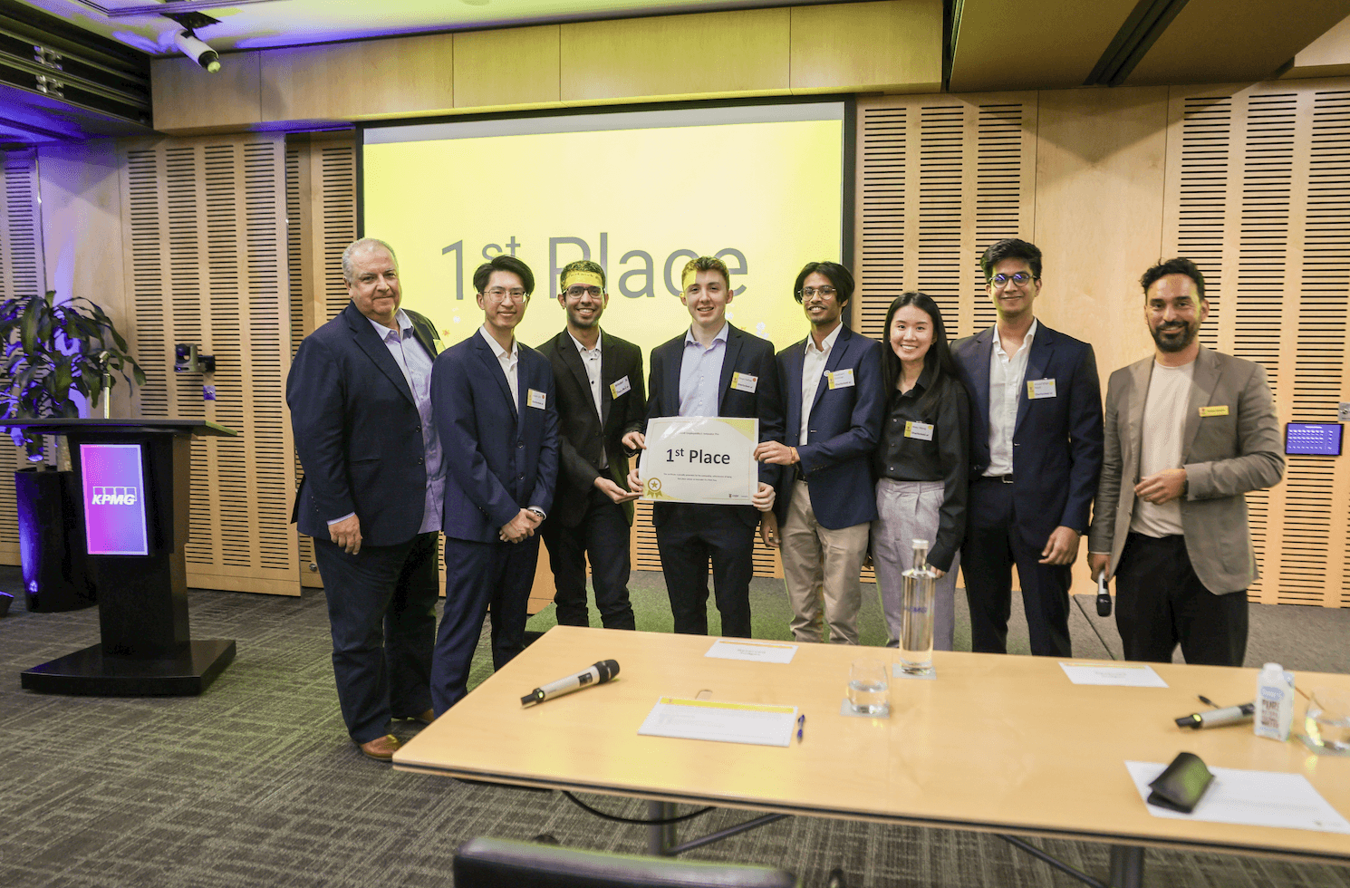 The team on stage after being announced first place at the pitch competition, a first place slide behind them.
